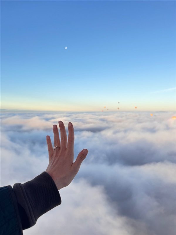 Mano con anillo de compromiso sobre las nubes desde el globo en Marrakech